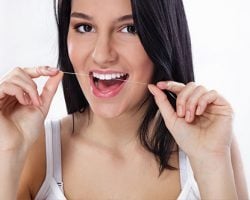Lady using a floss to clean her teeth | The Foehr Group in Bloomington, IL | Dr. Wolf